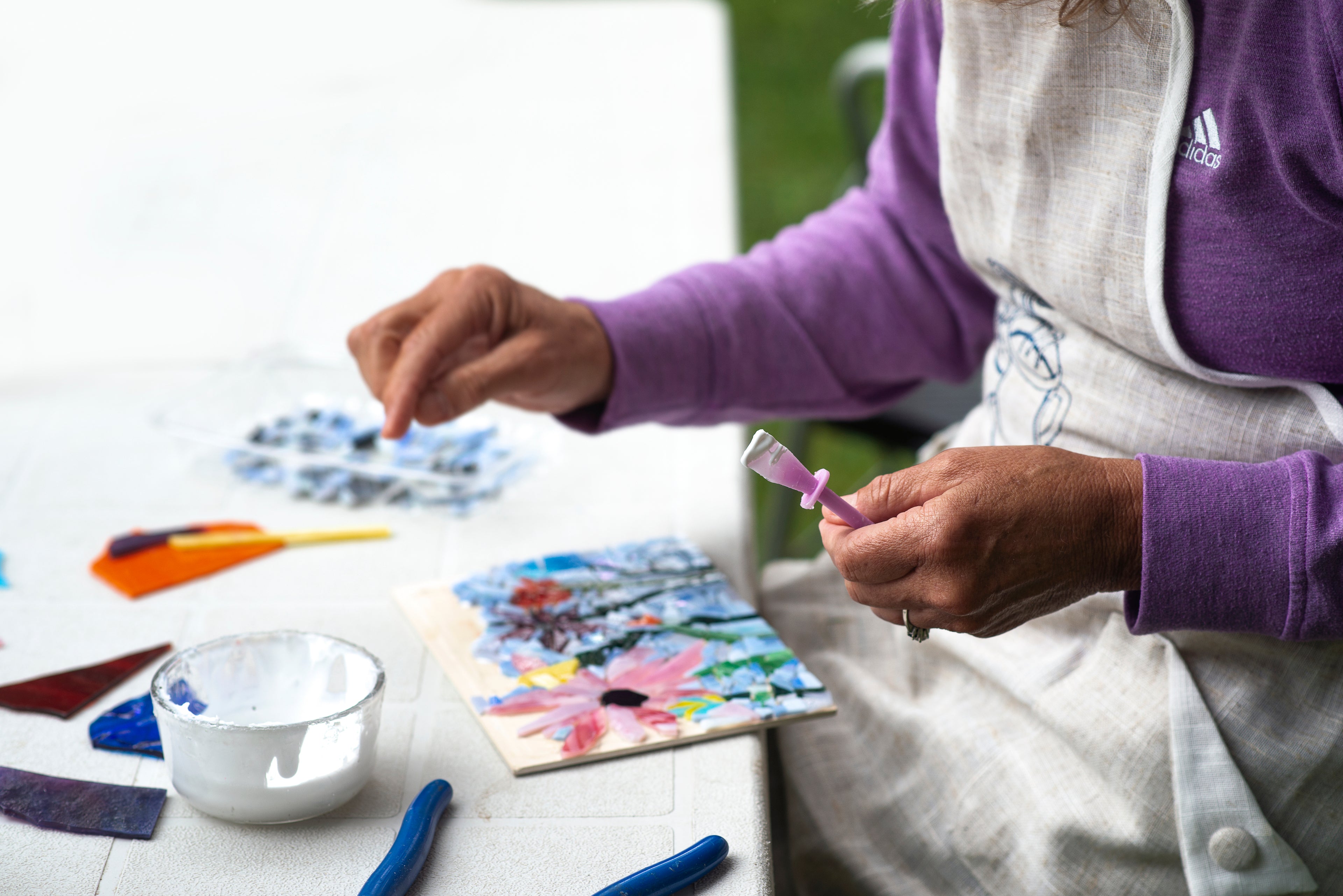 artist works on a floral mosaic with white paint